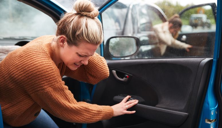 woman holding neck getting out of car